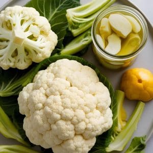 Jar of homemade pickled cauliflower with fresh cauliflower.