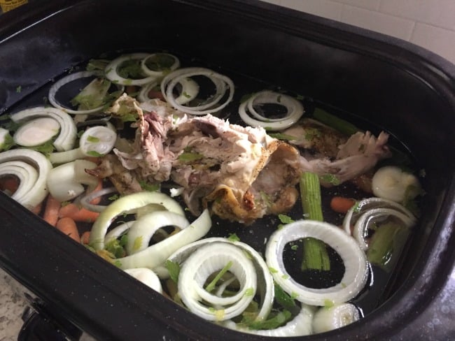 Homemade chicken broth cooking in an electric dutch oven