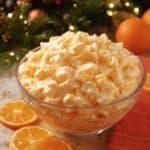 Orange fluff salad topped with mandarin slices in a glass serving bowl