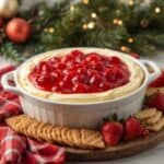 Bowl of creamy cherry cheesecake dip topped with cherry pie filling and graham crackers
