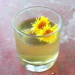 Glass of dandelion iced tea garnished with fresh dandelion flowers