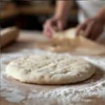 A homemade pizza with a bubbly sourdough crust topped with melted mozzarella and fresh basil.