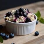 Freshly made blueberry crisp served warm with a scoop of vanilla ice cream on top.