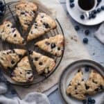 Freshly baked blueberry scones on a cooling rack with a drizzle of glaze