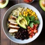 Healthy Mexican burrito bowl with grilled chicken, black beans, avocado, and lime