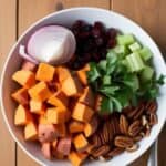 Bowl of colorful sweet potato salad with cranberries and nuts
