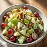 Bowl of classic Waldorf salad with diced apples, celery, grapes, and walnuts in creamy dressing