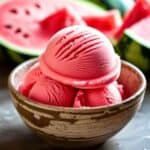 Close-up of a spoon scooping smooth watermelon sorbet from a glass bowl