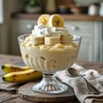 Close-up of creamy banana pudding topped with banana slices and vanilla wafers in a white bowl