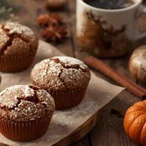 Fresh gingerbread muffins with powdered sugar on a rustic table