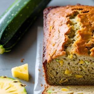 Slice of moist pineapple zucchini bread with nuts on a plate
