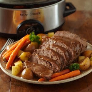 Tender slow cooker pot roast with carrots and potatoes in a rustic bowl