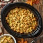 Slow cooker chicken dressing in a crockpot with herbs and golden stuffing