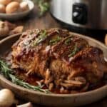 Juicy shredded pork shoulder in a slow cooker with herbs and sauce