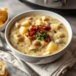 Bowl of creamy clam chowder topped with crispy bacon and parsley