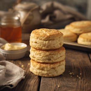 golden sourdough biscuits stacked on a plate with butter