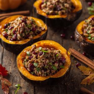 Stuffed acorn squash halves filled with sausage and herbs on a rustic table