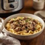Slow cooker beef stroganoff topped with fresh parsley on a rustic table