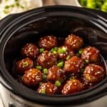Teriyaki meatballs served in a white bowl garnished with sesame seeds and fresh scallions.