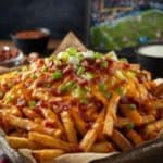 Close-up of cheesy loaded fries with crispy bacon bits and scallions