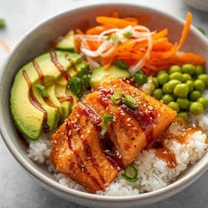 A bowl of crispy cubed salmon with avocado, cucumber, and rice.