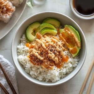 A wooden bowl containing fresh crab salad, avocado, and cucumber over a bed of seasoned white rice.