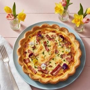 Rustic Quiche Lorraine surrounded by roasted vegetables for brunch