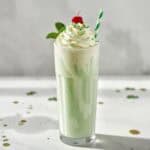 Creamy green Shamrock Shake in clear glass with striped straw